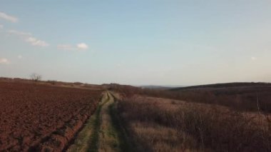 Tarım arazisi yakınlarındaki kırsal yolun havadan görünüşü, verimli toprak, ilkbahar günü. İnsansız hava aracına göre video.