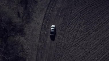 Kirli kırsal yollarda insansız hava aracıyla çekim yapan gri arabanın hava manzarası tek başına off-road yapıyor..