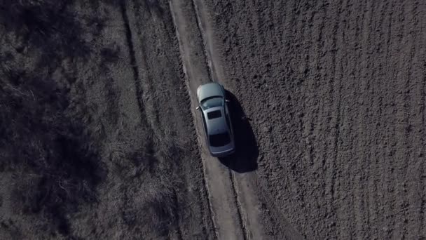 灰色の車の空中トップビューは 無人機によって撮影汚い農村道路上の単独でオフロードを駆動します — ストック動画