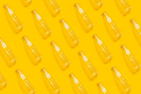 Pattern of transparent plastic bottles on yellow background. Photo collage.