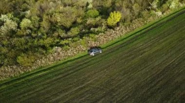 Gri arabanın havadan görünüşü tarım arazisi yakınlarındaki kırsal alanda tek başına off-road yapıyor. İnsansız hava aracıyla çekim. İlkbahar Günü.