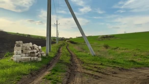 晴れた日 青い空の背景にコンクリート電気柱高電圧線を介して農業分野の農村道路 — ストック動画