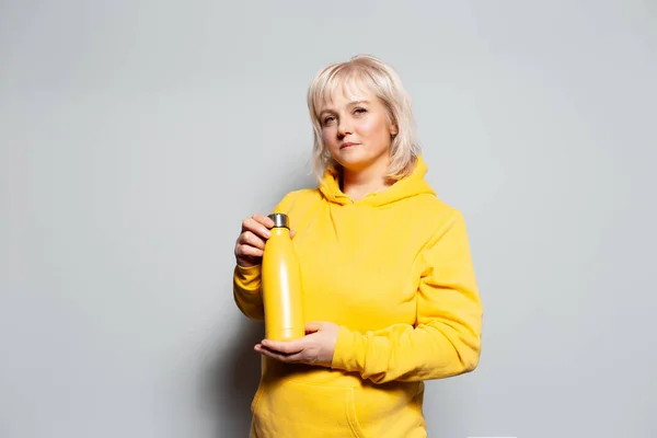 工作室肖像严肃的金发女人拿着白色背景的金属热水瓶 — 图库照片