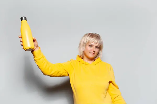 金发碧眼的女人拿着白色底色的不锈钢热水瓶的画像 — 图库照片