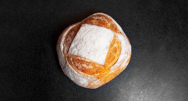 Yuvarlak ekmeğin yakın çekim görüntüsü siyah desenli masanın arka planında. Panoramik pankart görünümü.