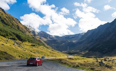 Dağlarda kırmızı araba. Transfagarasan 'daki Romen Karpatlar' ın doğal manzarası. Bulutlu bir sonbahar günü.