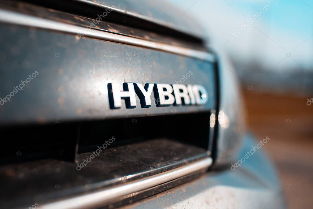 Close-up of Hybrid icon on dirty car body. Environment concept. Ecological transport.