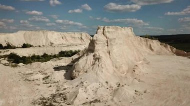 Mavi gökyüzünün arka planında kumdan kaya zirvesinin havadan görünüşü. İnsansız hava aracı görüntüleri. Beyaz kum tepeleri. Doğal soyut doğa arkaplanı.