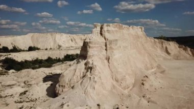 Mavi gökyüzünün arka planında kumdan kaya zirvesinin havadan görünüşü. İnsansız hava aracı görüntüleri. Beyaz kum tepeleri. Doğal soyut doğa arkaplanı.