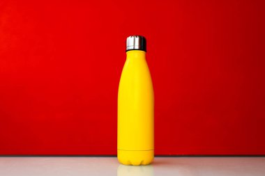 Kırmızı zemin üzerinde sarı çelik termo su botu.