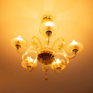 Ilık bir ışık saçan avizenin yakın görüntüsü.