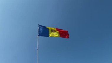 Moldova Cumhuriyeti bayrağı mavi gökyüzünün arka planında rüzgarda dalgalanıyor.