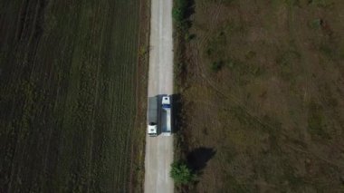Kargolu kamyonun hava görüntüsü beyaz kırsal bir yolda ilerliyor. İnsansız hava aracı görüntüleri.