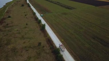 Kargolu kamyonun hava görüntüsü beyaz kırsal bir yolda ilerliyor. İnsansız hava aracı görüntüleri.