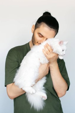 Beyaz arka planda beyaz kedisi olan gülümseyen bir adamın portresi..