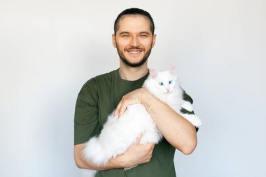 Beyaz arka planda beyaz kedisi olan gülümseyen bir adamın portresi..