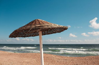 Deniz ve gökyüzünün arka planına karşı sahilde bambu şemsiyesi yakın plan..
