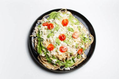 Beyaz arka planda siyah yuvarlak tabakta vejetaryen makarna..