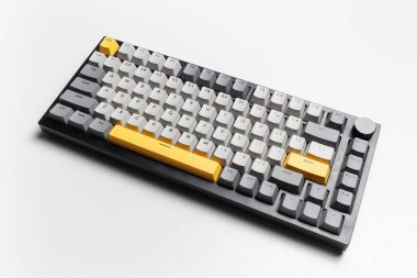 Beyaz arkaplandaki bilgisayar için mekanik klavye. Gri, siyah ve sarı renklerin anahtar başlığı.