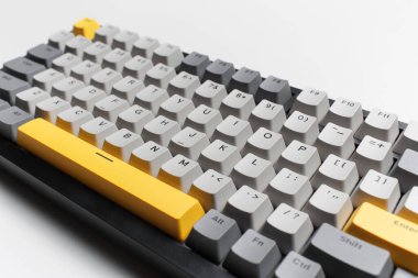 Beyaz arkaplandaki bilgisayar için mekanik klavye. Gri, siyah ve sarı renklerin anahtar başlığı.