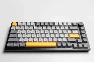 Beyaz arkaplandaki bilgisayar için mekanik klavye. Gri, siyah ve sarı renklerin anahtar başlığı.