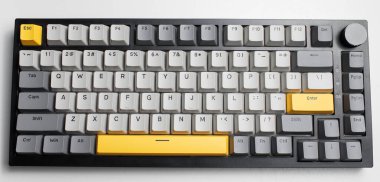 Beyaz arkaplandaki bilgisayar için mekanik klavye. Gri, siyah ve sarı renklerin anahtar başlığı.