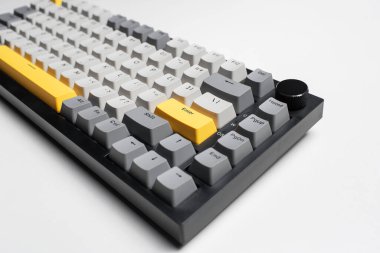 Beyaz arkaplandaki bilgisayar için mekanik klavye. Gri, siyah ve sarı renklerin anahtar başlığı.