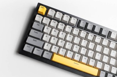 Beyaz arkaplandaki bilgisayar için mekanik klavye. Gri, siyah ve sarı renklerin anahtar başlığı.