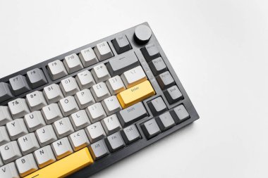 Beyaz arkaplandaki bilgisayar için mekanik klavye. Gri, siyah ve sarı renklerin anahtar başlığı.