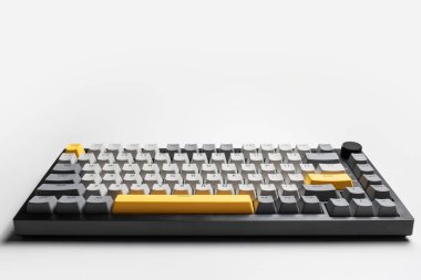 Beyaz arkaplandaki bilgisayar için mekanik klavye. Gri, siyah ve sarı renklerin anahtar başlığı.