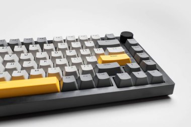 Beyaz arkaplandaki bilgisayar için mekanik klavye. Gri, siyah ve sarı renklerin anahtar başlığı.