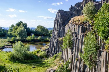 Ağaçların yetiştiği görkemli bazalt dağları. Çek Cumhuriyeti 'nin enginliğinde çubuk şeklinde altıgen taş dağlar