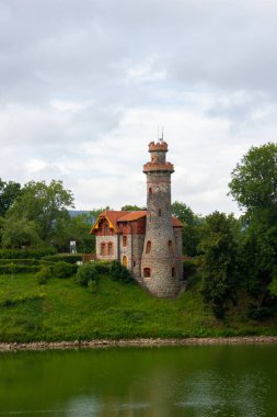 Çek Cumhuriyeti 'nin Hradec Krlov kasabasında pencereleri ve kırmızı çatısı olan antik taş su kulesi. Arkaplanda yeşil ağaçlar