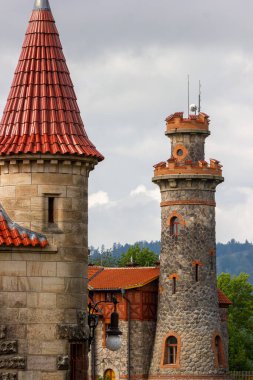 Çek Cumhuriyeti 'nin Hradec Krlov kasabasında pencereleri ve kırmızı çatısı olan antik taş su kulesi. Arkaplanda yeşil ağaçlar