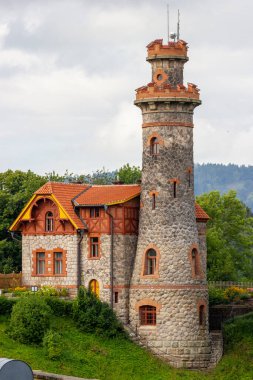 Çek Cumhuriyeti 'nin Hradec Krlov kasabasında pencereleri ve kırmızı çatısı olan antik taş su kulesi. Arkaplanda yeşil ağaçlar