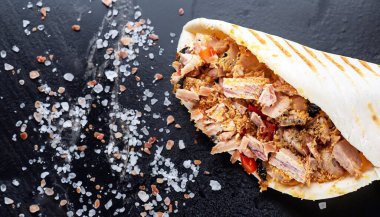 Marullu ve zeytinli tavuklu tortilla dürümü siyah mermer taşlı tabakta.