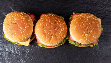 Çeşitli malzemelerle doldurulmuş üç lezzetli tavuk, sığır eti ve karides burgerine düşük açılı ön manzara. Kopyalama alanı içerir. Sıra üç hamburger.