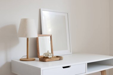 Modern bir lamba ve gümüş renkli balkabağı olan ahşap tepsiyle dikey boş çerçeveler. Çağdaş iç tasarım, ev, ofis masaüstü. Güzel doğal yıldırımla yan manzara.