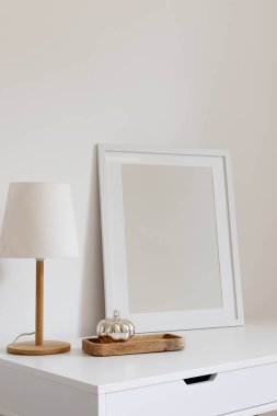 Modern bir lamba ve gümüş renkli balkabağı olan ahşap tepsiyle dikey boş çerçeve modeli. Minimalist iç tasarım, ev, ofis masaüstü.