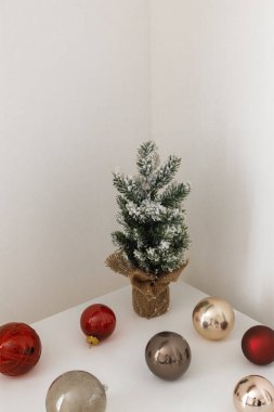 Duvardaki beyaz masada suni Noel ağacıyla süslenmiş Noel mücevherleri. Minimalist bütünsellik kavramı.