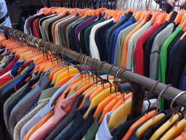 Marketteki askıya paralel olarak dizilmiş bir kıyafet koleksiyonu.