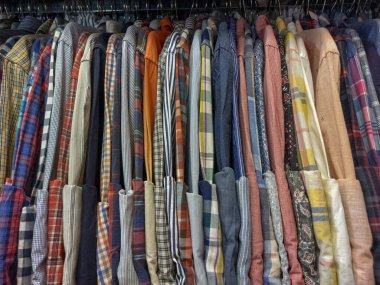 Çeşitli motiflere sahip fanila gömlekler bir giyim mağazasında sıra sıra asılır.