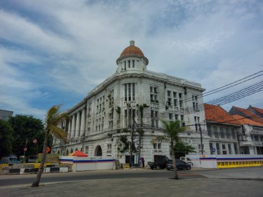 Yolun kenarındaki beyaz koloni tarzı bina perspektif açısından çekilmiş.