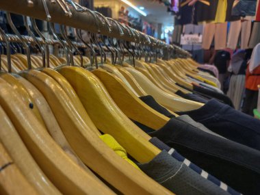 Bir giyim mağazasında sıraya dizilmiş ahşap elbise askıları.