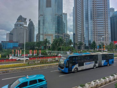 Transjakarta bus is passing on the capital's highway with a background of skyscrapers clipart