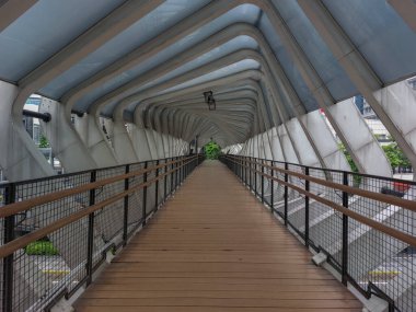 Ahşap zeminli ve gelecekten gelen çatılı yaya köprüsü.