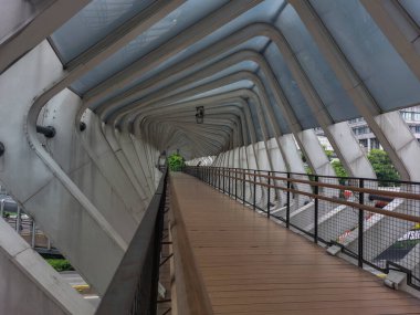 Ahşap zeminli ve gelecekten gelen çatılı yaya köprüsü.