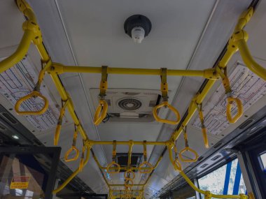 Transjakarta otobüsünün içindeki sarı tırabzanlar.
