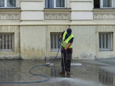 Novi Sad, 3 Temmuz 2023. - Buhar temizleme kaldırımı basınçlı, çelik yelekli adam