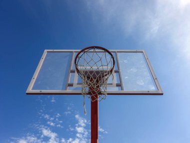 Aşağıdan ağlı basketbol potası gökyüzü arka planına sahip açık bir sahada